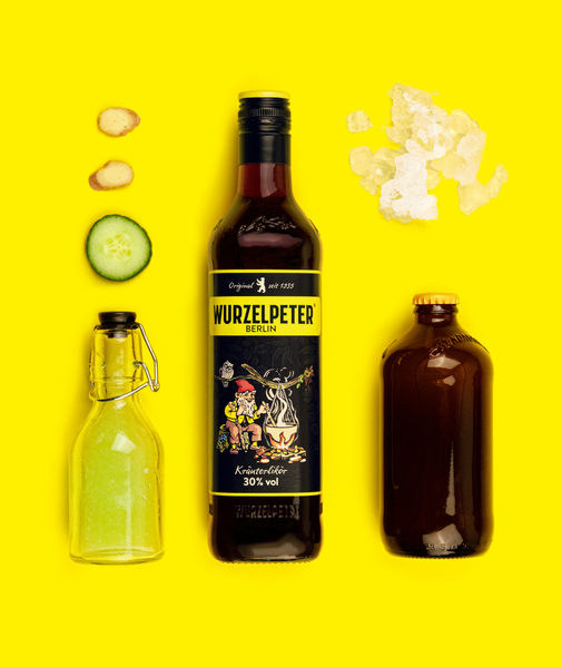 Ein leuchtend gelbes Bild mit einer Flasche Wurzelpeter Kräuterlikör, umgeben von frischen Zutaten wie Gurke und Ingwer.