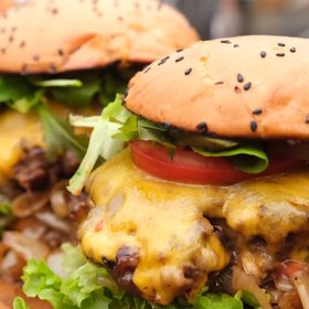 Nahaufnahme von köstlichen Burgern, die mit frischen Zutaten und einem goldbraunen Brötchen angerichtet sind.