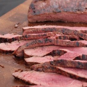 Saftige, perfekt geschnittene Rindersteaks liegen auf einem Holzbrett, mit einer leicht rauchigen Kruste und rosa Innenseite.