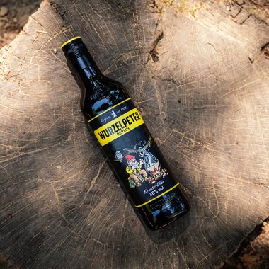 In der Dämmerung halten mehrere Personen eine Flasche Wurzelpeter und stoßen mit kleinen Gläsern an, um zu feiern.