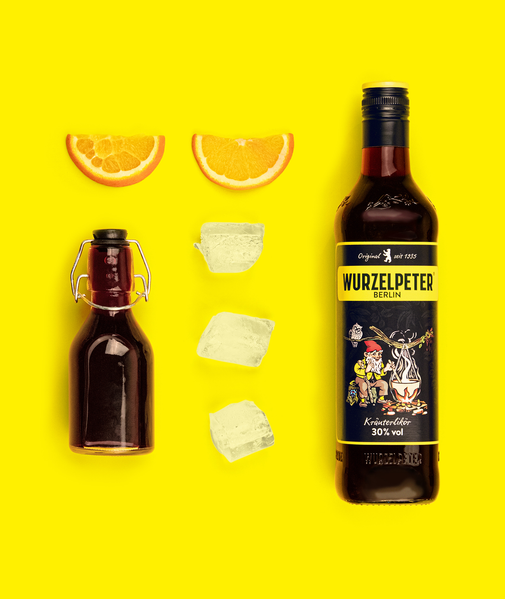 Ein leuchtend gelbes Bild zeigt eine Flasche Kräuterlikör, umgeben von Orangenscheiben und Eiswürfeln.