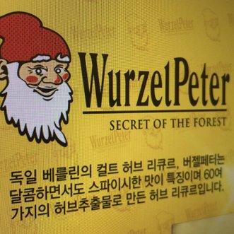Ein fröhlicher Zwerg mit rotem Hut und weißem Bart lächelt auf einem gelben Hintergrund, der den Namen 'WurzelPeter' trägt.